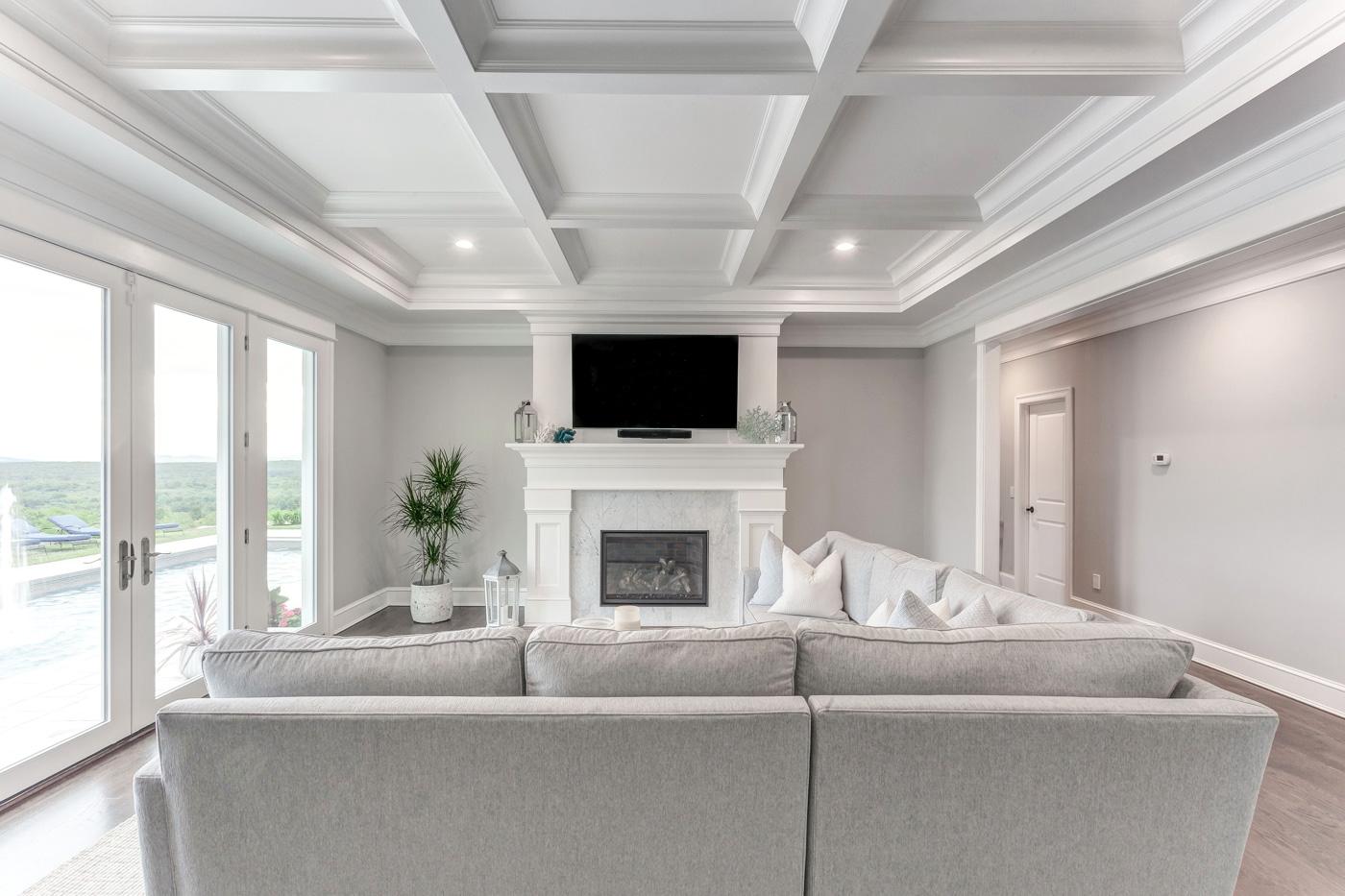 A custom-built mantel and recessed coffered ceiling by Laplante Construction